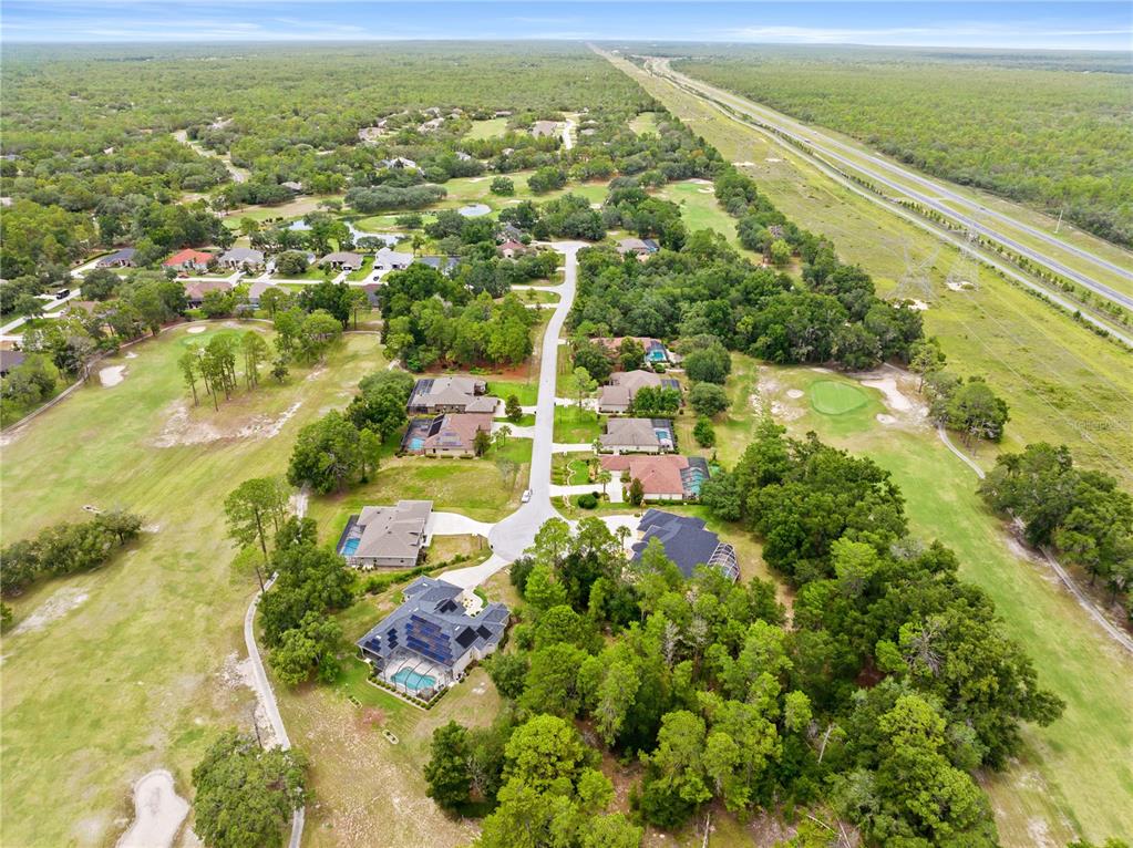 An aerial view shows houses situated along a golf course near a highway — 17 WOODLEE COURT S, HOMOSASSA, FL