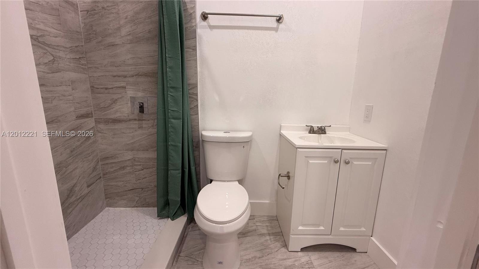 A bathroom features a tiled walk-in shower, a white toilet, and a small vanity cabinet — 17614 SW 134th Pl # B, Miami FL 33177, MIAMI, FL