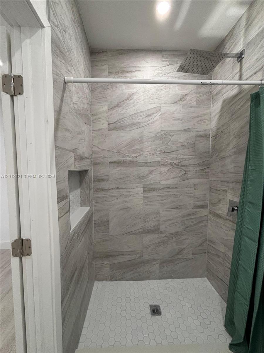 A tiled walk-in shower features a rainfall showerhead, a recessed niche, and a green curtain — 17614 SW 134th Pl # B, Miami FL 33177, MIAMI, FL