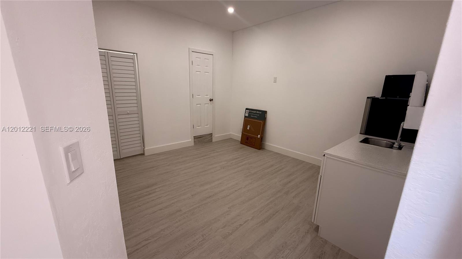 This room features light wood-look flooring, white walls, a small kitchenette, and two doors — 17614 SW 134th Pl # B, Miami FL 33177, MIAMI, FL