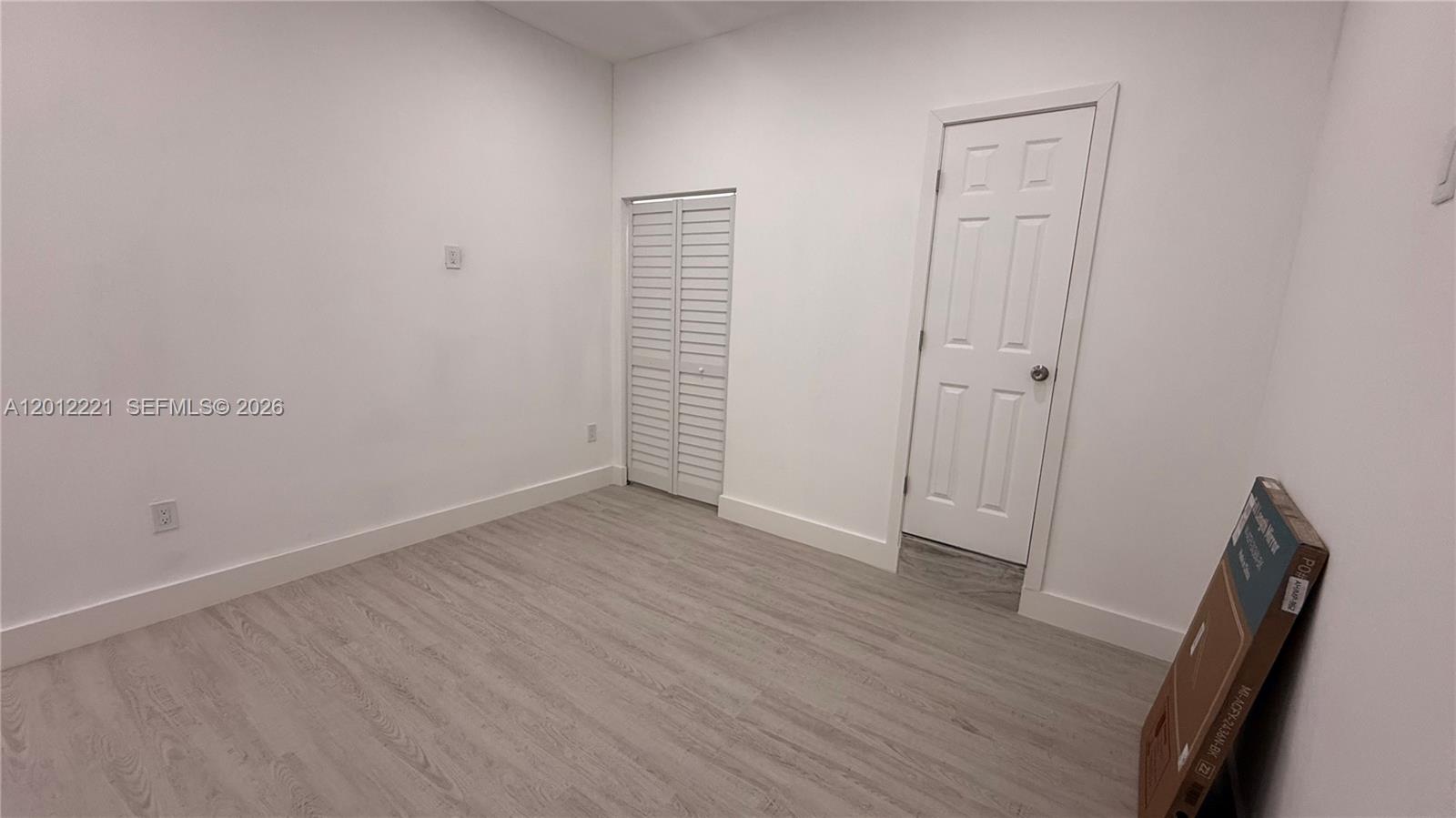 An empty room features white walls, light wood-look flooring, a closet, and a standard door — 17614 SW 134th Pl # B, Miami FL 33177, MIAMI, FL
