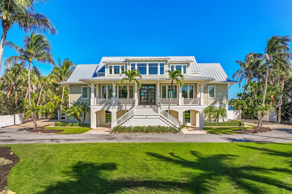 A two-story coastal home with a metal roof, elevated porch, and surrounding palm trees — 4070 LOOMIS AVENUE, BOCA GRANDE, FL