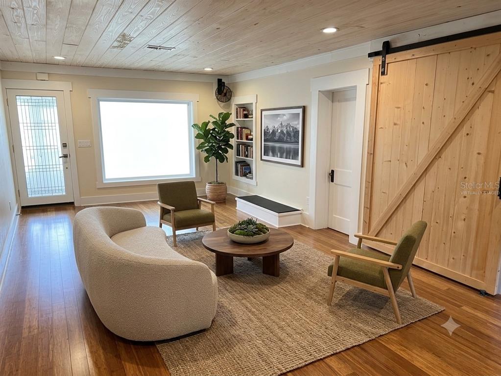 A living room features a curved sofa, two green chairs, a wood ceiling, and barn door — 301 E KENTUCKY AVENUE, DELAND, FL
