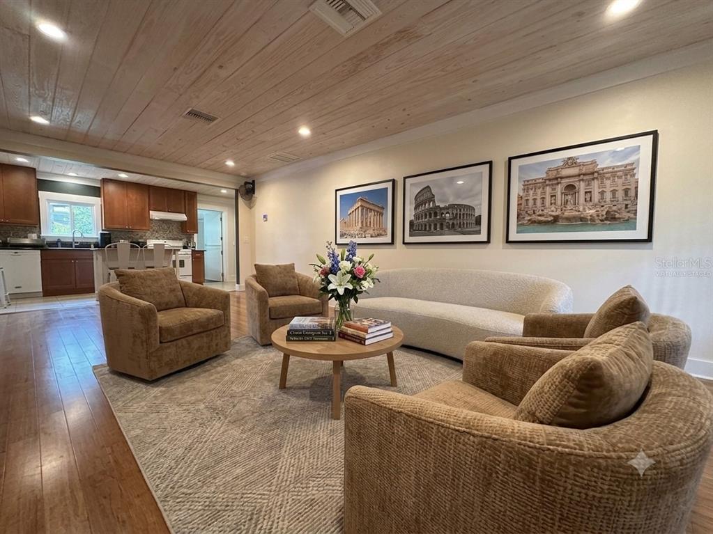 A living room with a wood-plank ceiling, brown armchairs, a curved sofa, and framed art — 301 E KENTUCKY AVENUE, DELAND, FL