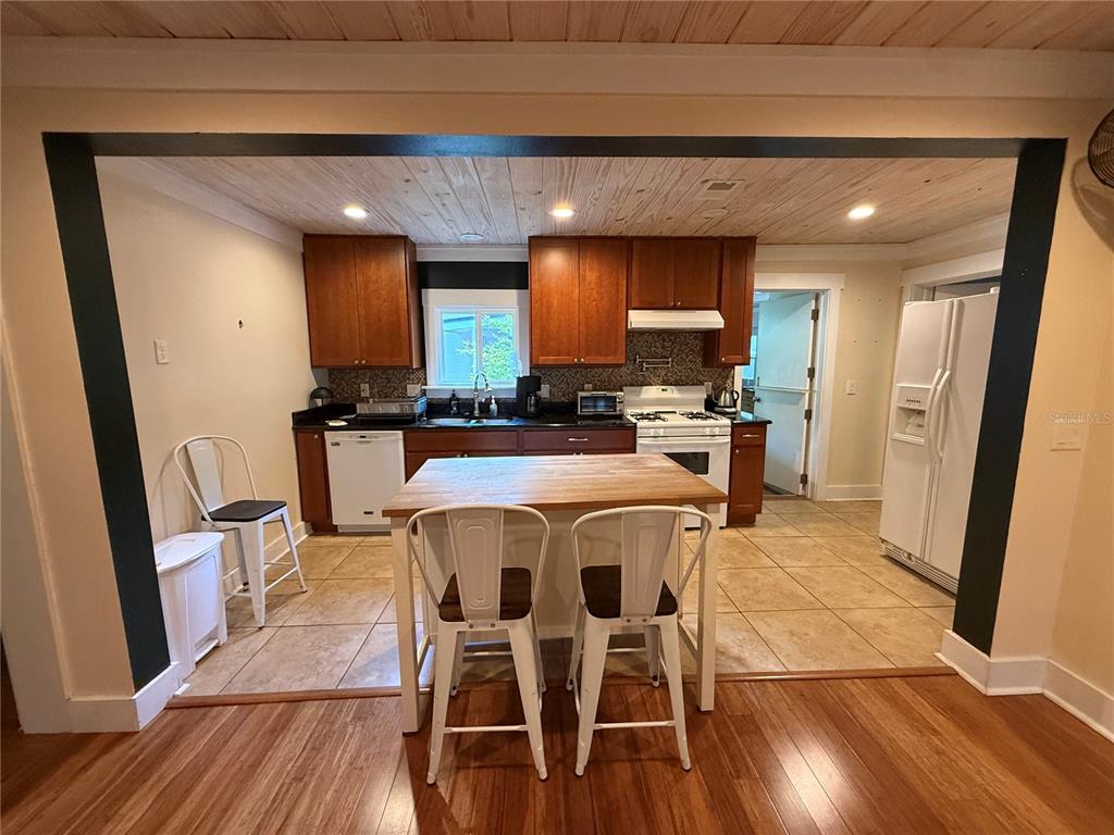 A kitchen features wood cabinets, a butcher block island, and a light-colored tile floor — 301 E KENTUCKY AVENUE, DELAND, FL