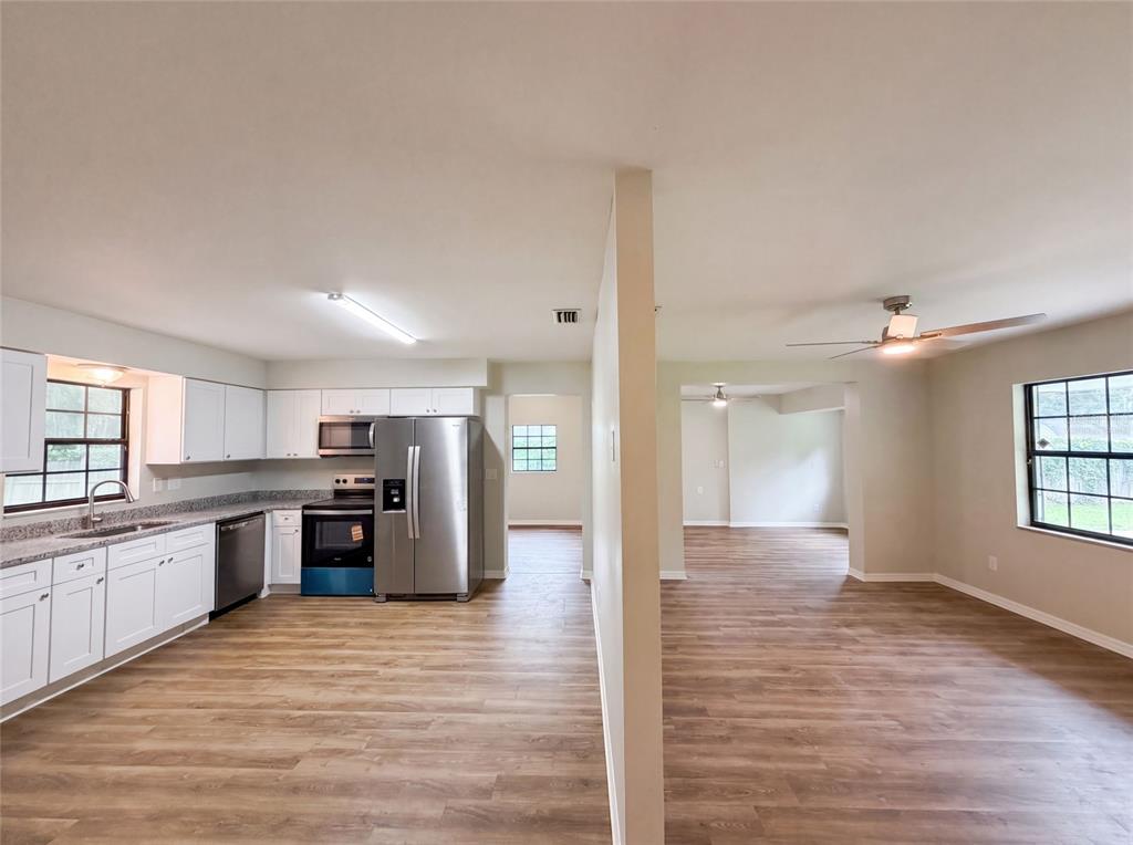 A kitchen with white cabinets and stainless steel appliances opens into a living area — 6520 NW 61ST COURT, OCALA, FL