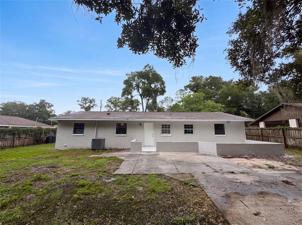 The exterior of a single-story concrete block house features a patio and a fenced yard — 6520 NW 61ST COURT, OCALA, FL