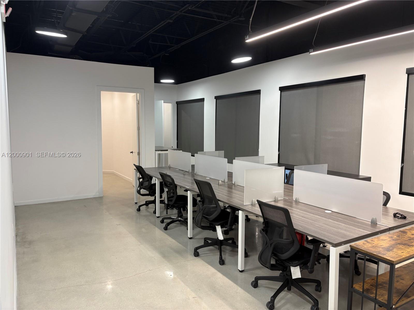 An office space features a long desk with privacy dividers, rolling chairs, and concrete floors — 1545 N Park Dr, Weston FL 33326, WESTON, FL