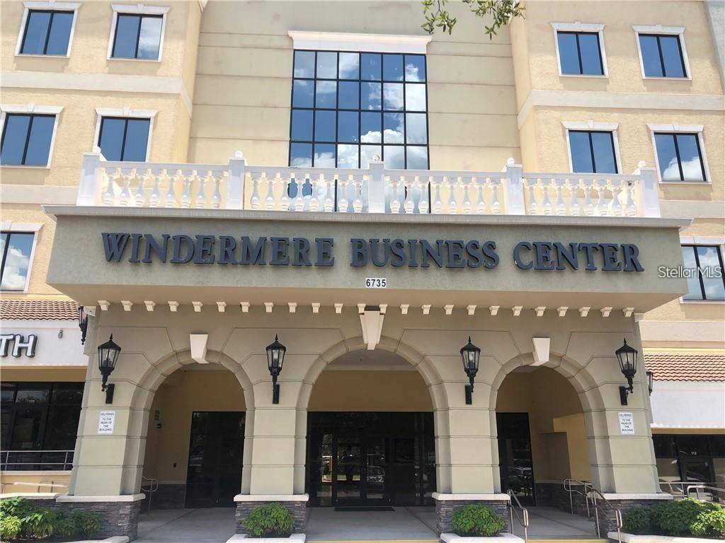 The exterior of a multi-story commercial building features an arched entrance and a business sign — 6735 CONROY ROAD UNIT 212, ORLANDO, FL