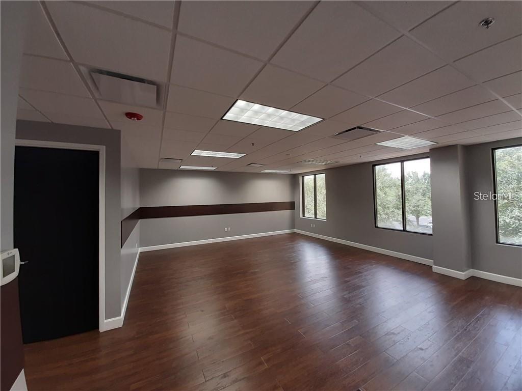 An empty office space features gray walls, dark wood flooring, and a drop ceiling — 6735 CONROY ROAD UNIT 212, ORLANDO, FL