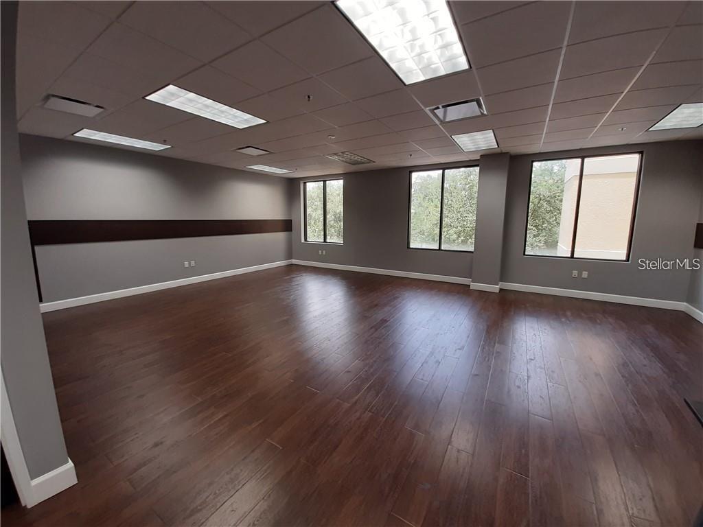 An empty office space features gray walls, dark wood flooring, and large windows — 6735 CONROY ROAD UNIT 212, ORLANDO, FL