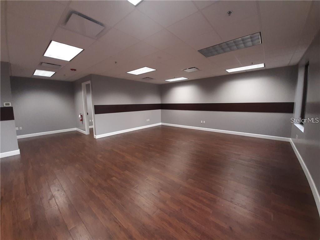 An empty office space features gray walls with a dark horizontal stripe and wood flooring — 6735 CONROY ROAD UNIT 212, ORLANDO, FL