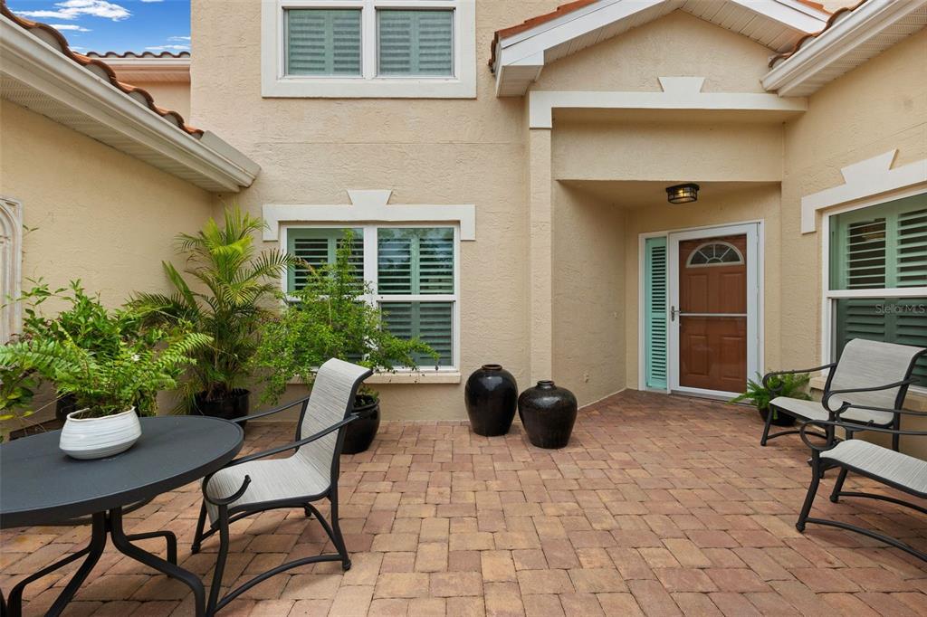 A paved patio area features outdoor furniture, potted plants, and a front entrance with a door — 264 WOODS POINT ROAD, OSPREY, FL