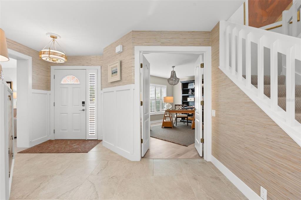 A bright foyer features beige grasscloth wallpaper, white wainscoting, tile flooring, and a staircase — 264 WOODS POINT ROAD, OSPREY, FL