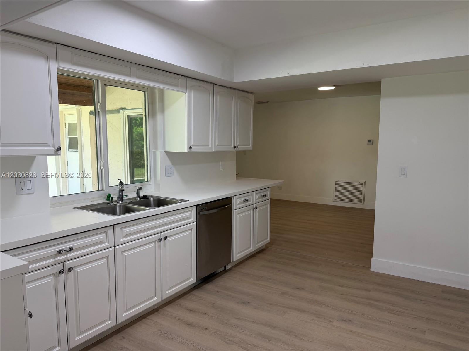 A kitchen features white cabinets, stainless steel appliances, and light wood-look flooring — 7220 NW 7th St, Plantation FL 33317, PLANTATION, FL