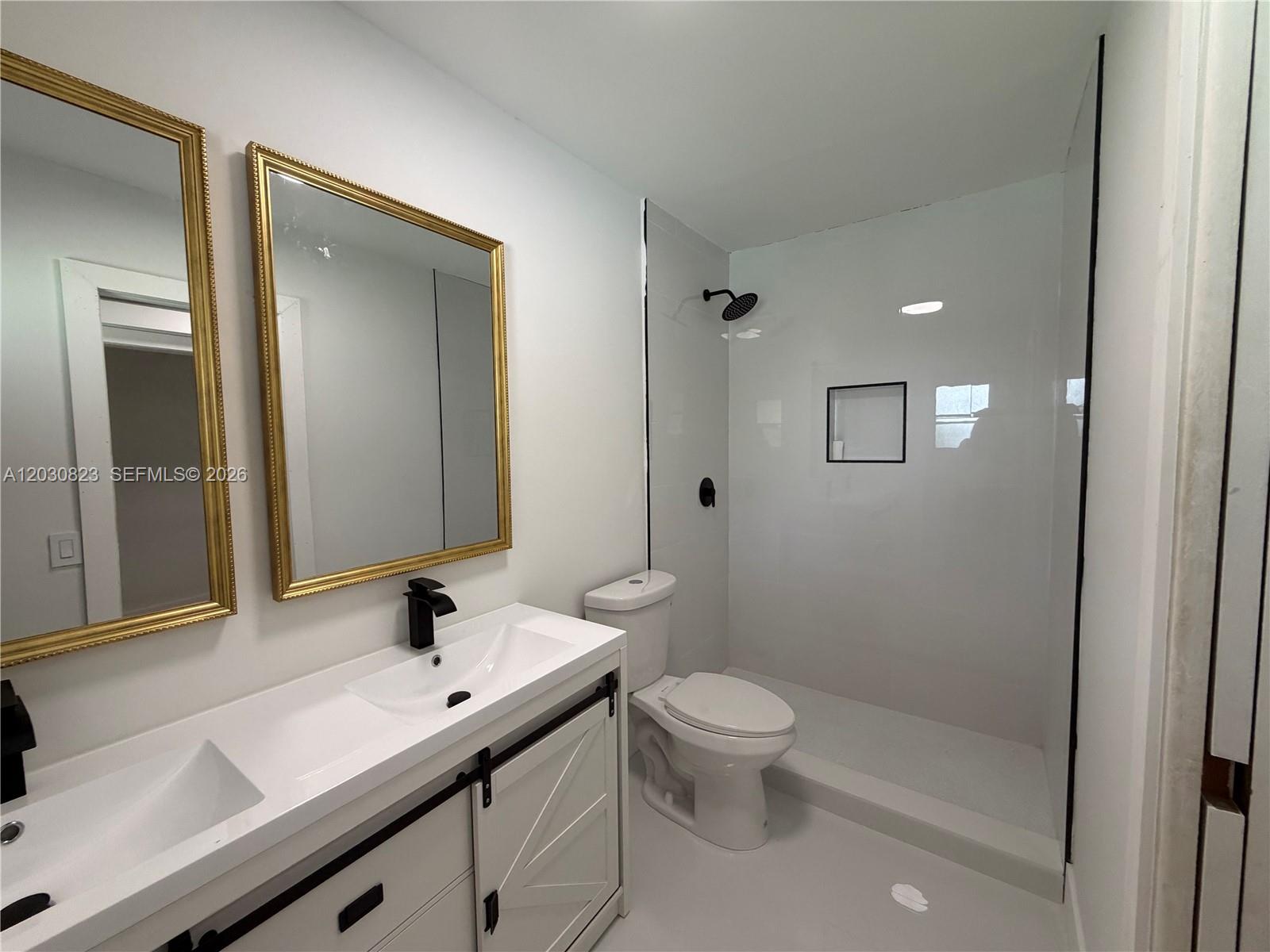 This bathroom features a double vanity with gold-framed mirrors, a toilet, and a walk-in shower — 7220 NW 7th St, Plantation FL 33317, PLANTATION, FL