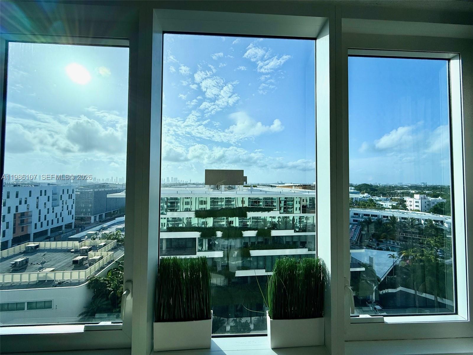 A view of a city skyline and buildings through three large, floor-to-ceiling windows — 2301 Collins Ave # 931, Miami Beach FL 33139, MIAMI BEACH, FL
