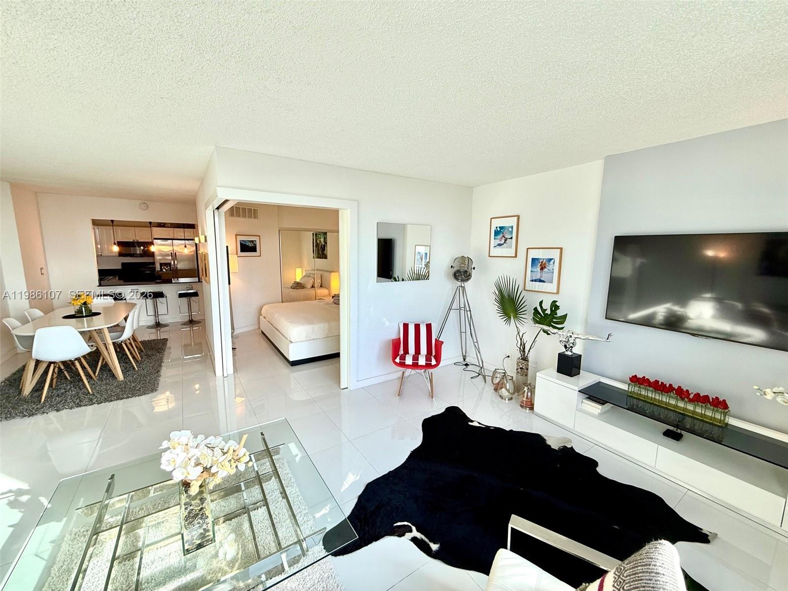 A bright living room with white tile floors, a black cowhide rug, and an adjacent bedroom — 2301 Collins Ave # 931, Miami Beach FL 33139, MIAMI BEACH, FL