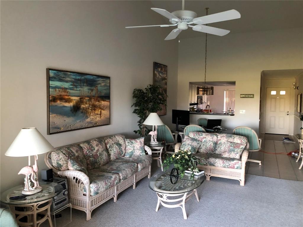 A living room features wicker furniture, floral cushions, a ceiling fan, and a pass-through kitchen — 6211 TIMBER LAKE DRIVE UNIT B4, SARASOTA, FL