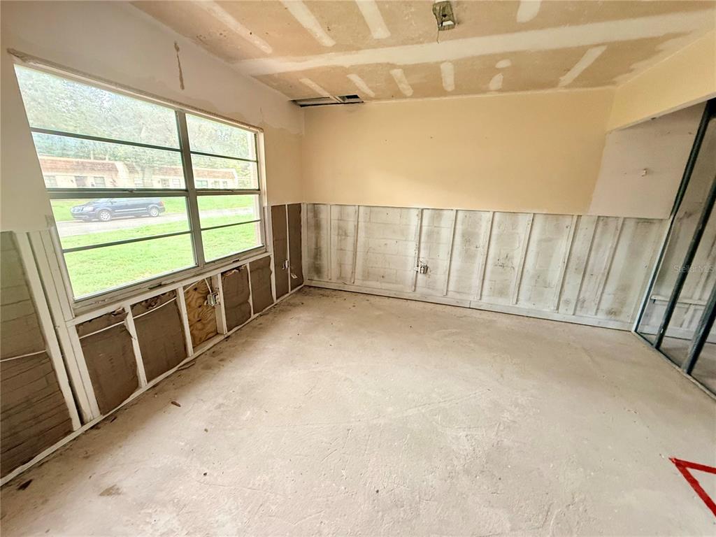 An unfinished room with exposed wall studs, concrete flooring, and large windows — 1380 MISSION CIRCLE UNIT 44-C, CLEARWATER, FL