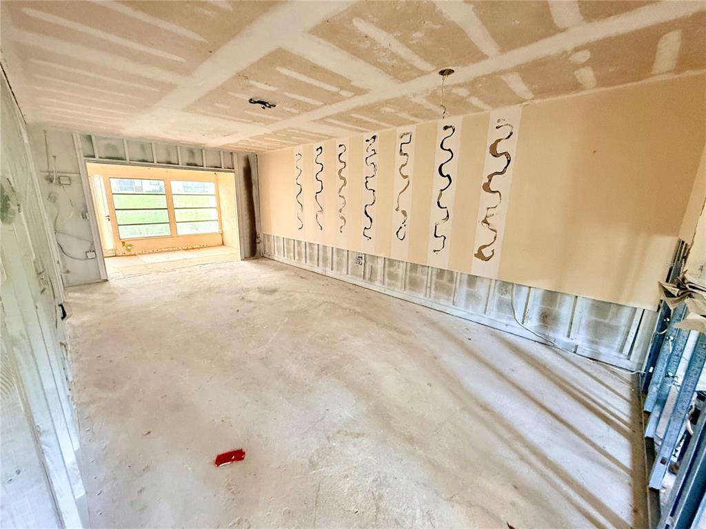 An unfinished room features exposed concrete block walls, drywall patches, and a view of a patio — 1380 MISSION CIRCLE UNIT 44-C, CLEARWATER, FL