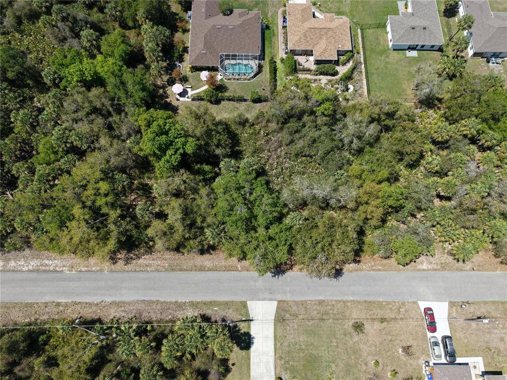 An aerial view shows a wooded lot situated across a road from residential homes — MCALLISTER LANE, NORTH PORT, FL