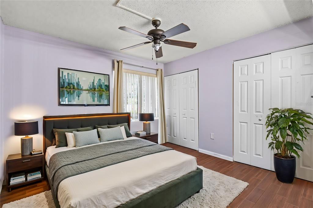 A bedroom features a bed with a green frame, wood flooring, and two white closets — 1810 NW 23RD BOULEVARD UNIT 202, GAINESVILLE, FL