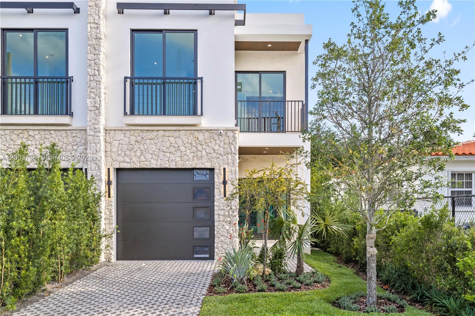 A modern two-story house features a stone facade, a dark garage door, and upper balconies — 3320 SW 23rd St, Miami FL 33145, MIAMI, FL