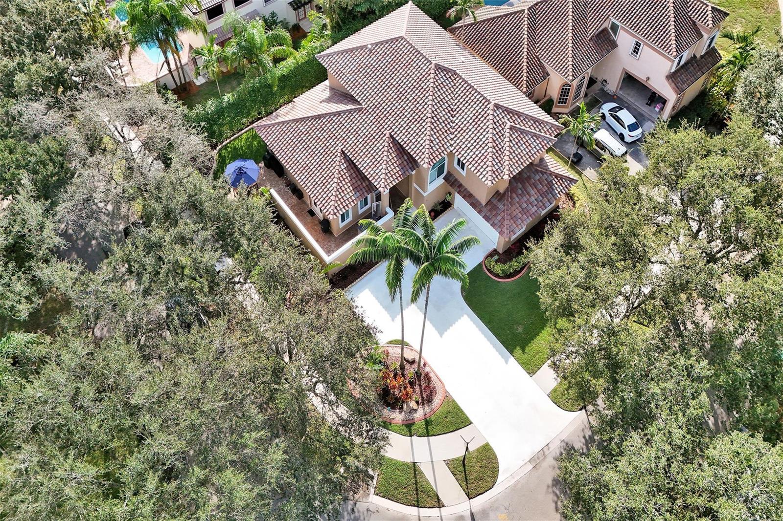 An aerial view of a two-story house with a tile roof, driveway, and palm trees — 11300 Knot Way, Cooper City FL 33026, COOPER CITY, FL