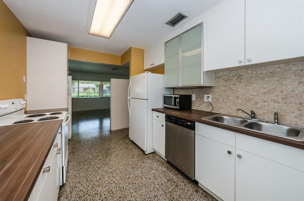 A kitchen features white cabinets, a dark wood countertop, stainless steel appliances, and terrazzo flooring — 5401 5TH AVENUE N, ST PETERSBURG, FL