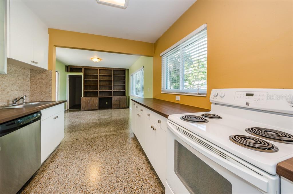 A kitchen with white cabinets, wood countertops, and terrazzo flooring leads into a living area — 5401 5TH AVENUE N, ST PETERSBURG, FL