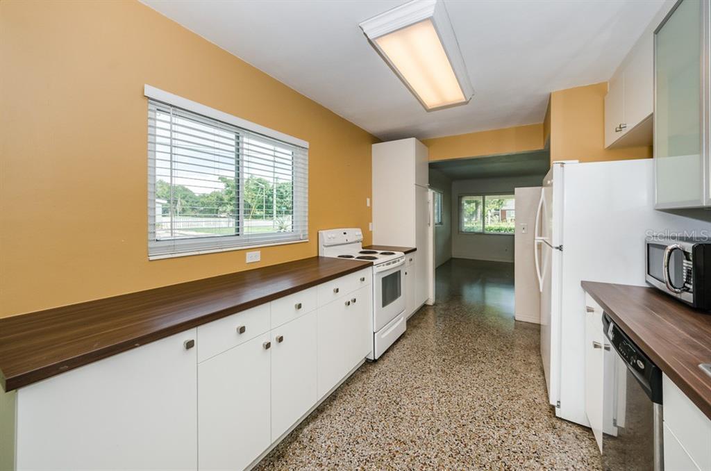 A kitchen features white cabinets, dark wood countertops, a white stove, and terrazzo flooring — 5401 5TH AVENUE N, ST PETERSBURG, FL