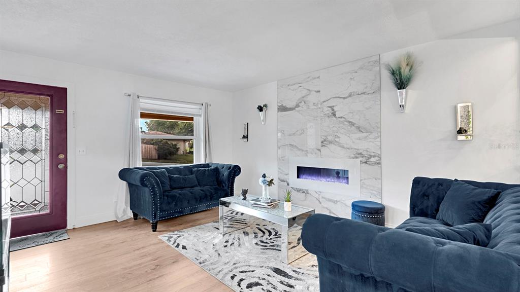 A living room features two navy blue sofas, a marble fireplace, and a glass coffee table — 1426 ELLEN LANE, APOPKA, FL