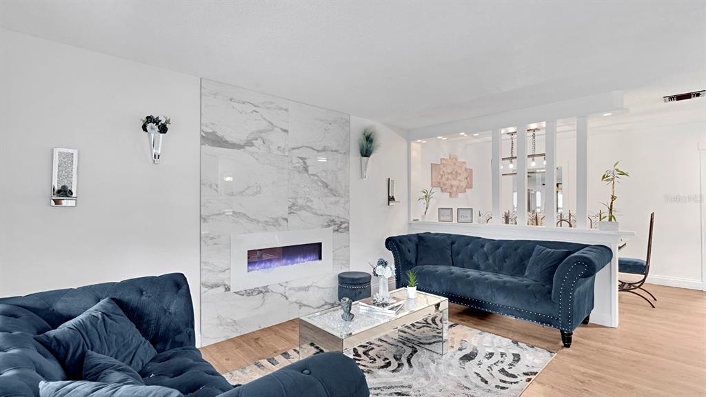 A living room features a marble fireplace, blue tufted sofas, and a mirrored coffee table — 1426 ELLEN LANE, APOPKA, FL