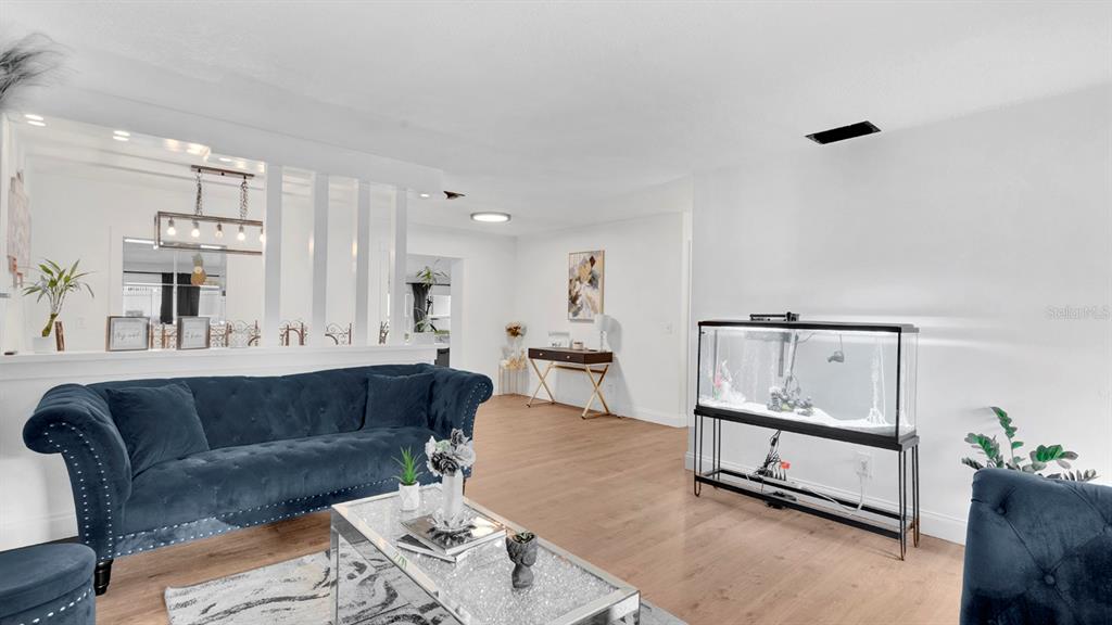 A living room features a blue velvet sofa, a glass coffee table, and a fish tank — 1426 ELLEN LANE, APOPKA, FL