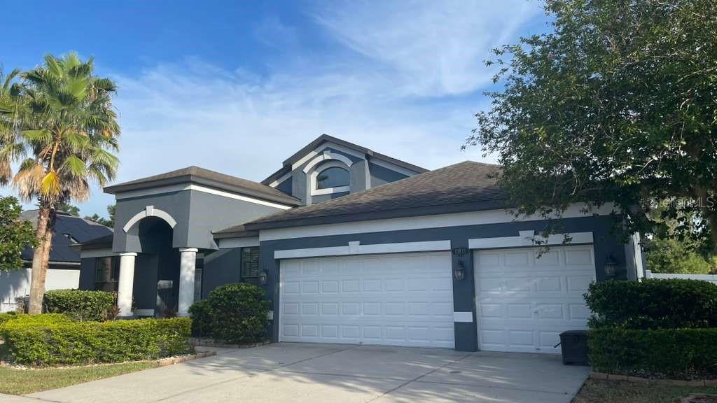 A gray single-story house with a two-car garage and a palm tree in the front — 11811 HARPSWELL DRIVE, RIVERVIEW, FL