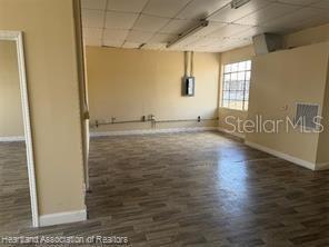 An empty room with light-colored walls, wood-look flooring, and a drop ceiling — 104 US 27 HIGHWAY S, AVON PARK, FL