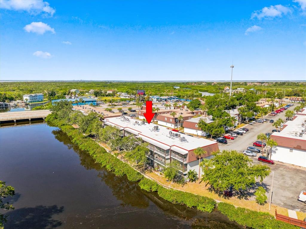 An aerial view shows a multi-story apartment building situated along a canal — 9009 TUDOR DRIVE UNIT G206, TAMPA, FL