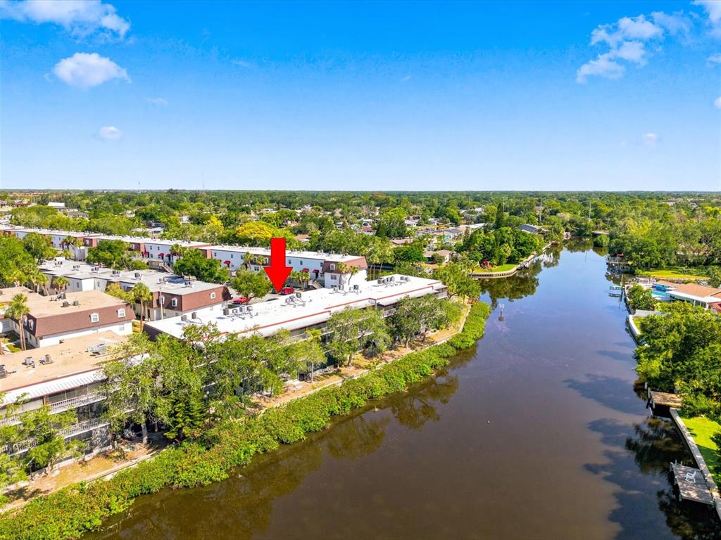An aerial view shows a multi-story apartment complex situated along a narrow river — 9009 TUDOR DRIVE UNIT G206, TAMPA, FL