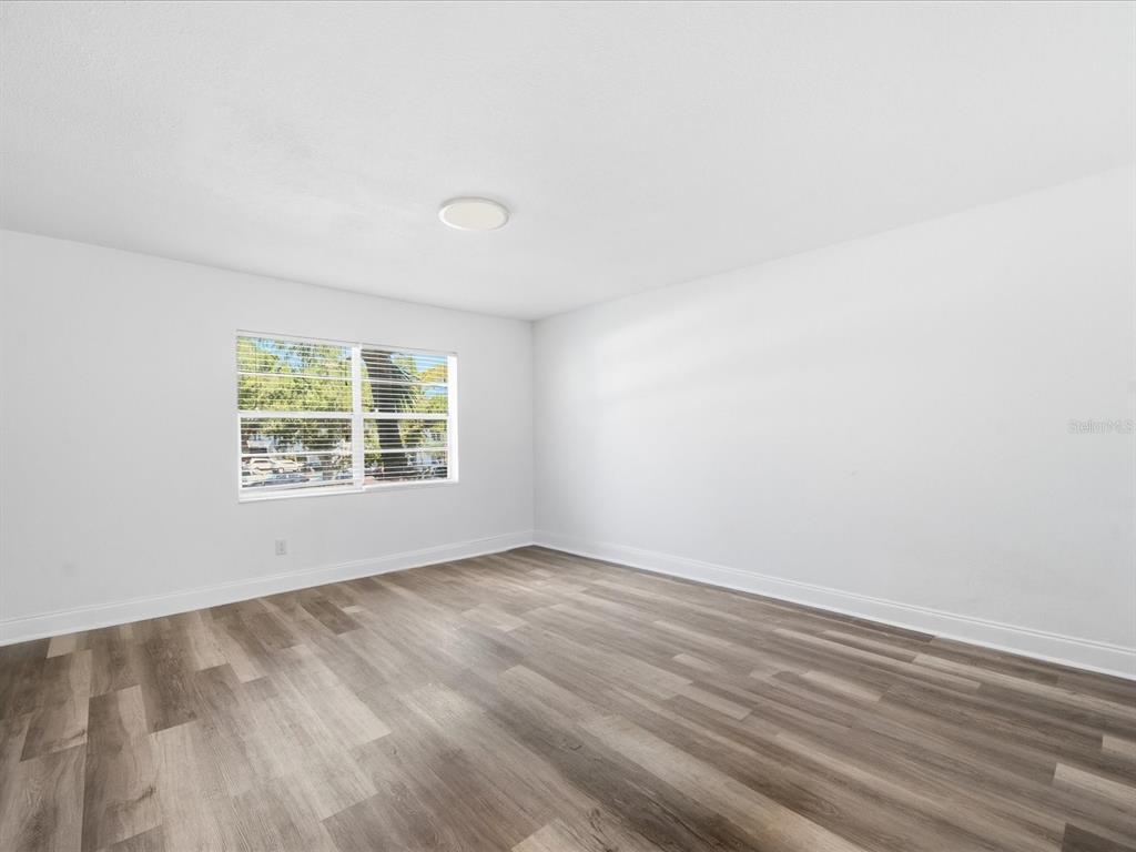 An empty room features white walls, a single window, and wood-look laminate flooring — 9009 TUDOR DRIVE UNIT G206, TAMPA, FL