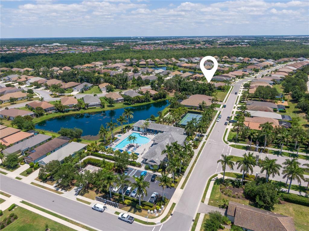 An aerial view shows a residential community with a clubhouse, swimming pool, and lake — 4226 MIDNIGHT BLUE RUN, BRADENTON, FL