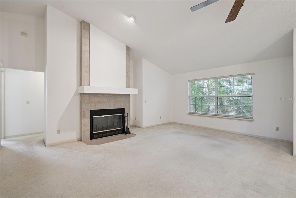 A living room features a fireplace with a tiled surround, carpeted floors, and a window — 1193 GLEN FALLS ROAD, DELAND, FL