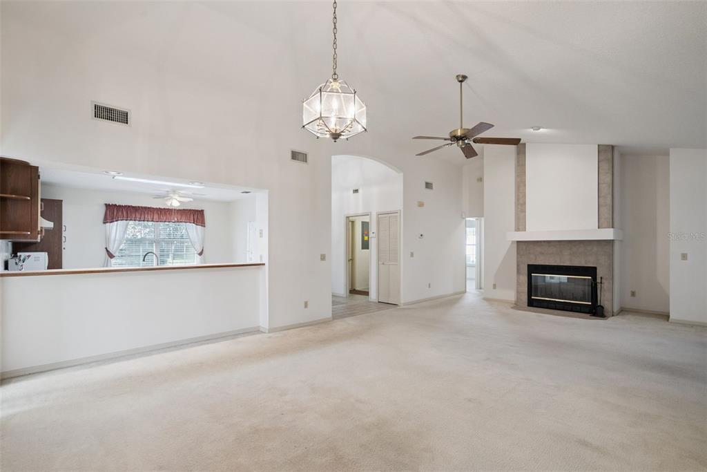 A spacious living room features a vaulted ceiling, a fireplace, and an open kitchen pass-through — 1193 GLEN FALLS ROAD, DELAND, FL