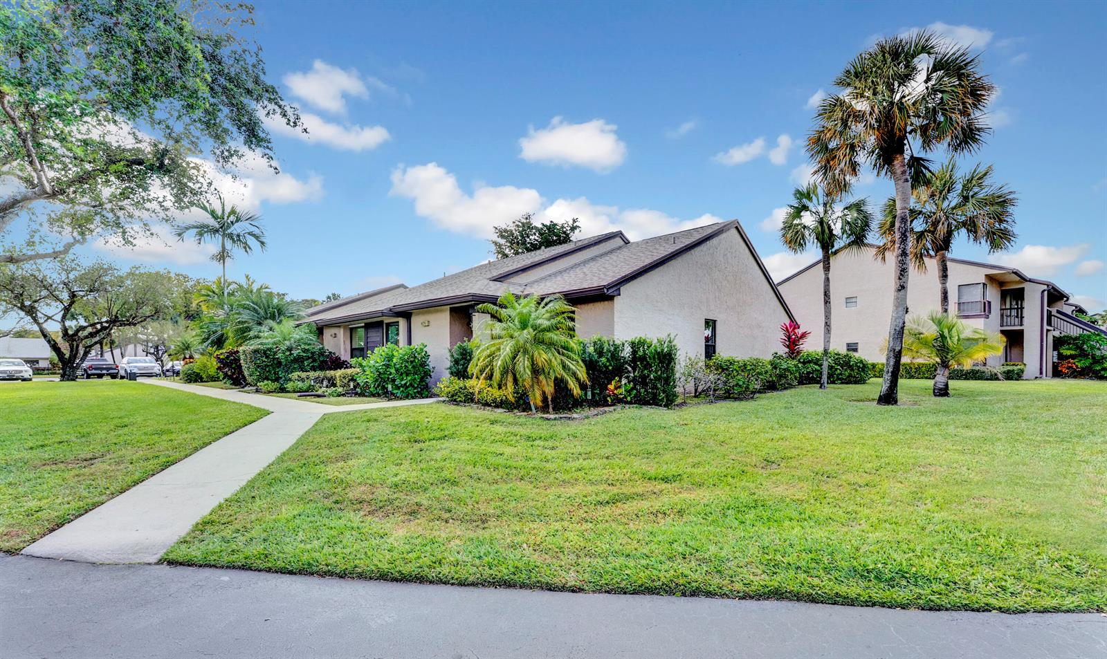 A single-story residential building with a tan stucco exterior sits on a grassy lawn — 8379 Boca Glades Boulevard E, Boca Raton FL 33434, BOCA RATON, FL