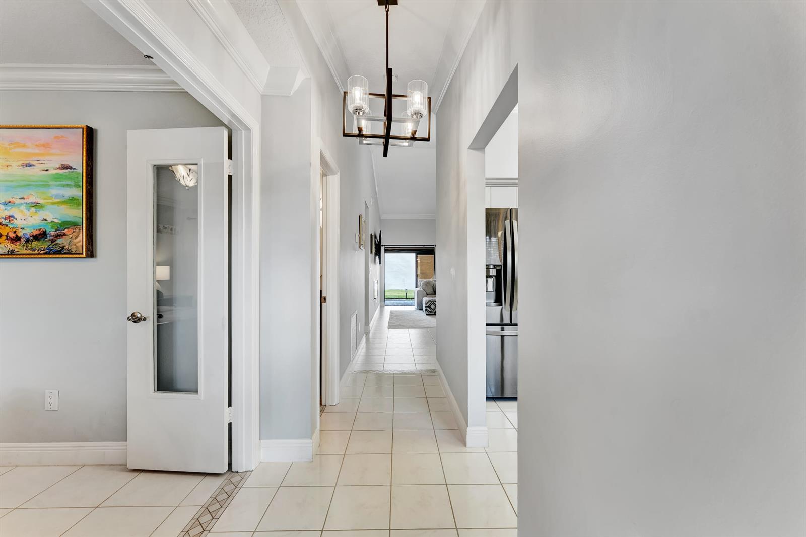 A hallway with light tile flooring leads toward a bright living area and kitchen — 8379 Boca Glades Boulevard E, Boca Raton FL 33434, BOCA RATON, FL