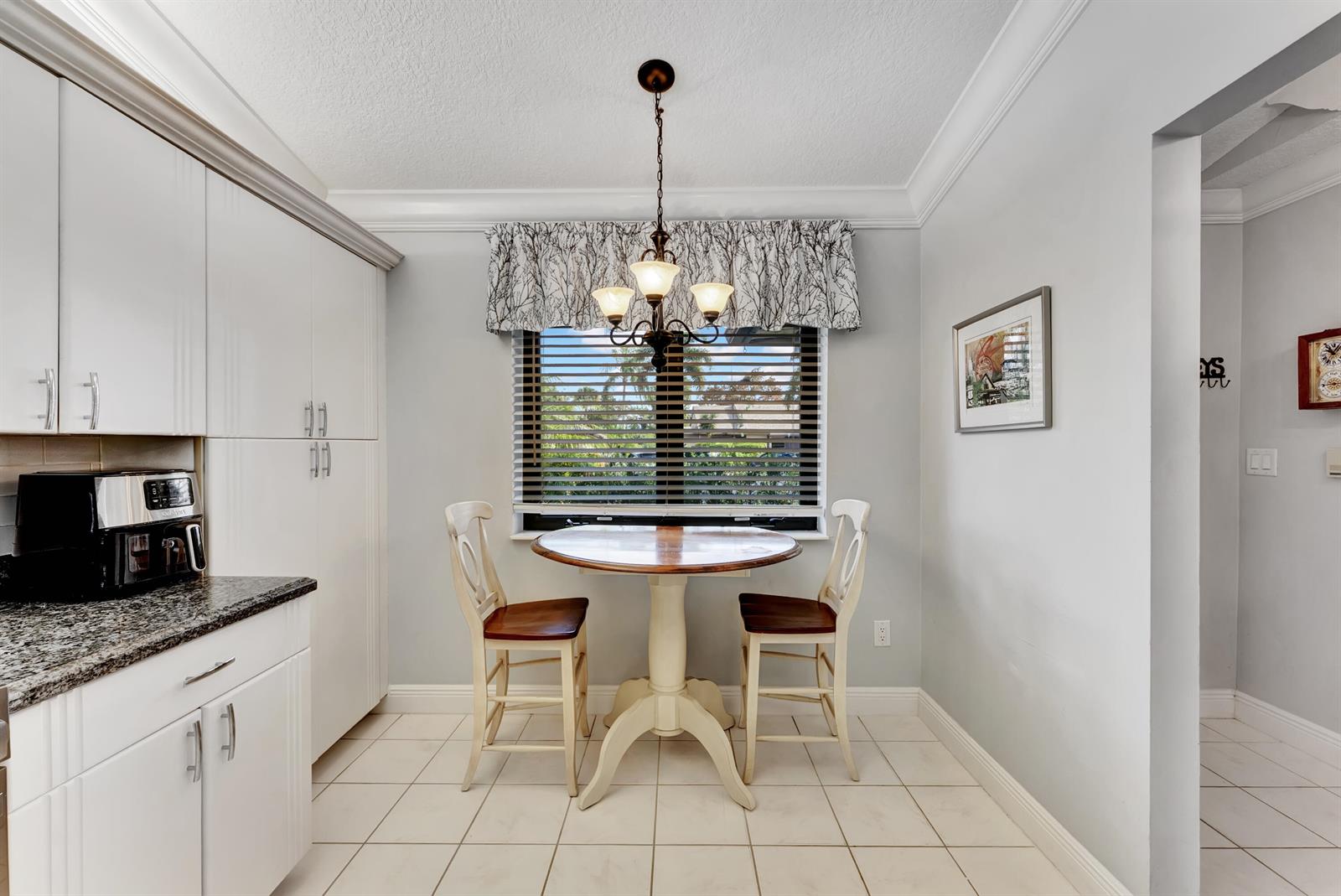 A kitchen breakfast nook features a round wooden table, two chairs, and white cabinetry — 8379 Boca Glades Boulevard E, Boca Raton FL 33434, BOCA RATON, FL