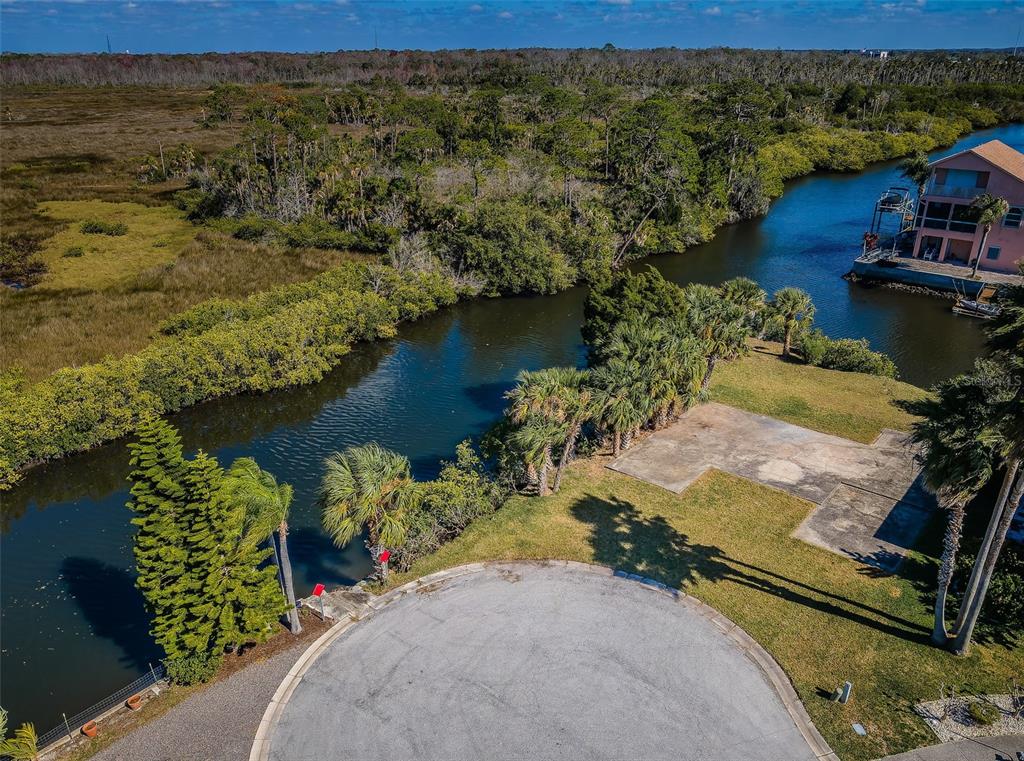 An aerial view shows a vacant waterfront lot with a concrete pad and palm trees — 0 SAN SIERRA WAY, PORT RICHEY, FL