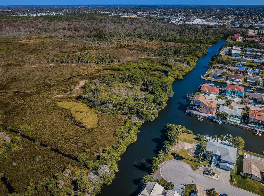An aerial view shows a canal winding past residential homes and a large undeveloped marshland — 0 SAN SIERRA WAY, PORT RICHEY, FL