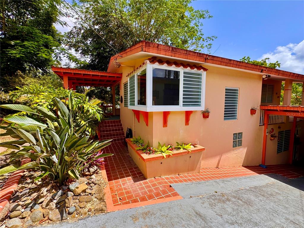A peach-colored house features a bay window, a tiled patio, and a covered entrance — 14 CHISTIAN BELÉN, AIBONITO, PR