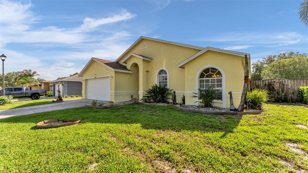 A yellow single-story house with a two-car garage and a front lawn under a blue sky — 7493 BRIARBAY LOOP, LAKELAND, FL